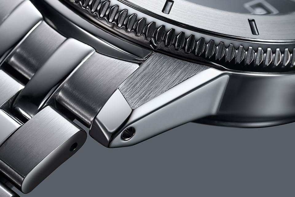 オリジナル・モデルを参考に、シャープで立体感溢れるカットが施されたラグ。ブレスレットはしなやかでフィット感に優れる5連リンクを採用。ウェットスーツの上からでも簡単にフィット感を調整できるエクステンション機構もバックルに装備している。