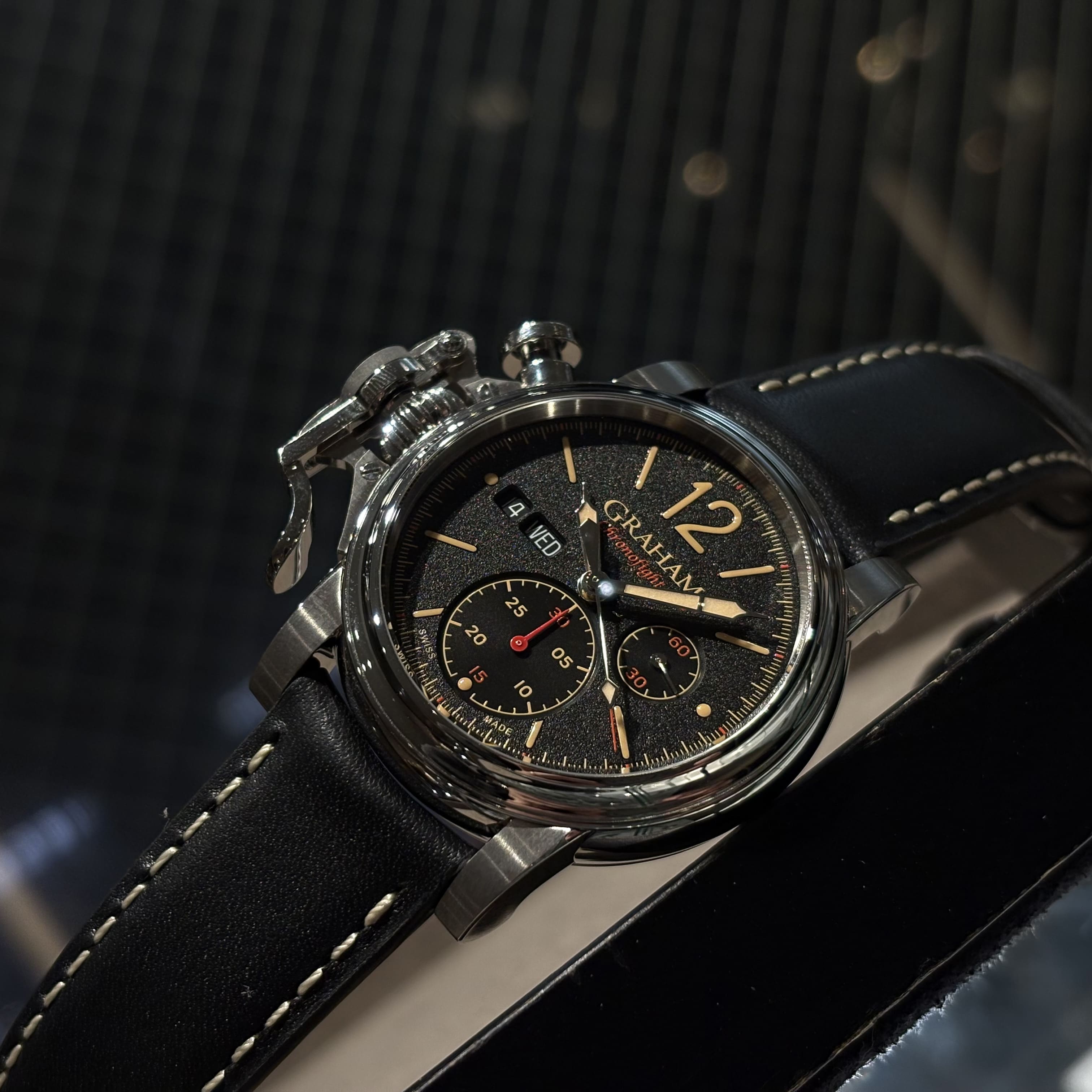 CHRONOFIGHTER VINTAGE LIGHT BROWN　2CVAS.B03AGRAHAM（グラハム）は、1995年にスイスで誕生したクロノグラフを中核とする機械式腕時計ブランド。偉大な時計師ジョージ・グラハムの名を冠し、他にはない大胆なデザインと力強い存在感を持つタイムピースを生み出してきました。象徴的な大型ケースやトリガー型クロノグラフプッシャーに代表される、ひと目でグラハムと分かる造形は、流行や無難さとは一線を画す“NOT EVERYBODY’S WATCH”という哲学を体現しています。堅牢なケース構造と本格的な機械式クロノグラフムーブメントを搭載し、視認性・操作性にも優れた実用的な腕時計でありながら、個性と主張を強く放つ一本。人と被らない時計を求める時計愛好家や、強いキャラクターを持つ腕時計を探している方にこそふさわしいブランドです。