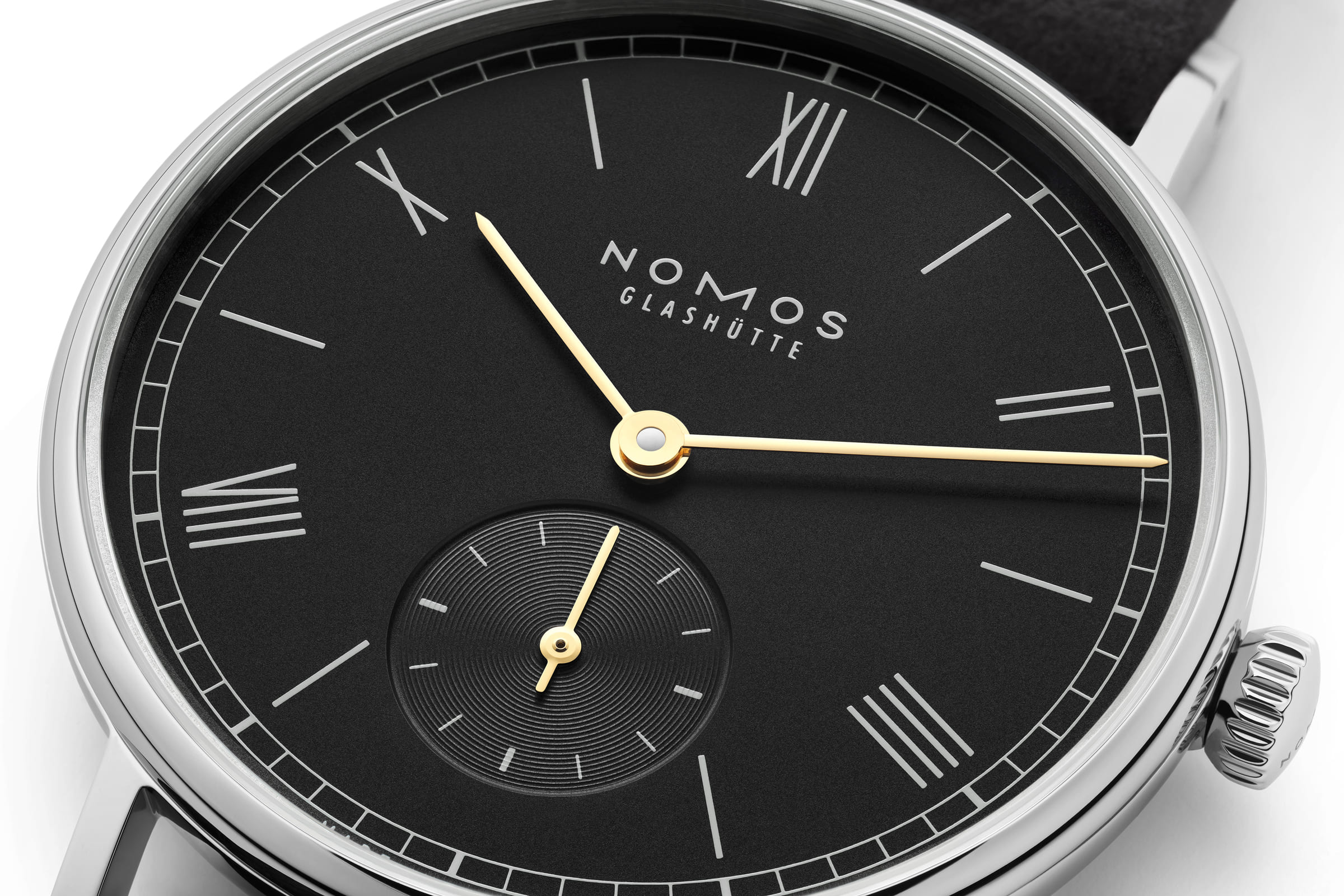 NOMOS Glashütte / Ludwig 33 noir / NM227　227繊細でエレガント、洗練された黒。  ノモス グラスヒュッテの新しい「ラドウィッグ 33 ノワール」は、夕刻の劇場やレセプション、ガラディナーなどで装うのにピッタリです。  ブラックの文字盤にゴールドの針。心地よい丸みを帯びた直径33ミリのケースに細身のベゼル。ストラップは暖かみのあるアンスラサイトカラーのベロアレザーを使いました。  カーブしたラグと優しい丸みを帯びたケースが快適な着け心地を実現し、アンスラサイトのベロアレザーストラップがラドウィッグの洗練性を引き立てます。  ローマン数字、わずかにくぼんだ秒針のサブダイヤル、伝統的なレイルウエイミニッツトラックを配したブラックの文字盤上を回るのは煌めくゴールドの3針。エレガントさを見事にアピールします。  ムーブメントは高精度で信頼性の高い手巻きキャリバー「α（アルファ）」を搭載。薄型のムーブメントのため時計全体のスリムなプロポーションに貢献しています。  女性はもちろん、男性にもお着けいただける小ぶりなサイズです。  シースルーバックの裏蓋からは丁寧な仕上げが施されたム