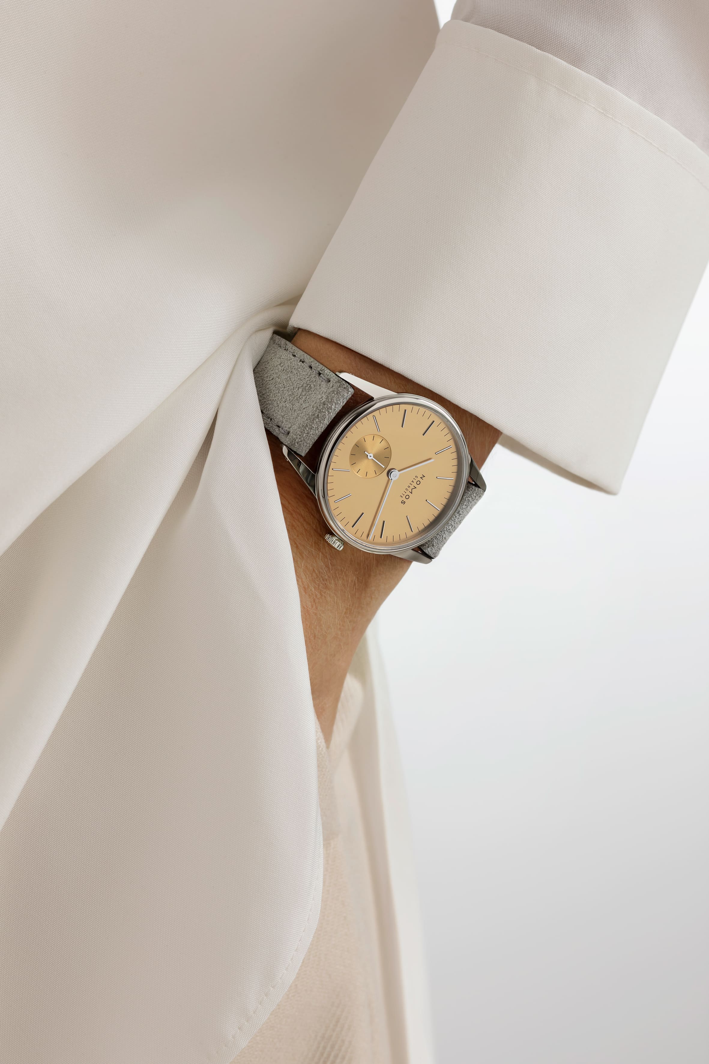 NOMOS Glashütte / ORION33/ OR1A3SG233　359ノモス グラスヒュッテのクラシックモデルの一つであるオリオンから、ギフトに最適な新作です。 オリオン 33 ゴールドとオリオン 38 シルバーは、特別な価値を持っています。 それは華やかだった「黄金の 1920 年代」を思い起こさせます。 オリオンはグラスヒュッテ伝統のデザインに回帰しました。 近年のミニマルデザインではなく、グラスヒュッテの時計学校でウオッチメーカーたちが製作していたデザインです。 銀色のケースに手作業で植えこんだインデックスをもつ文字盤です。 サイズは2 つあり、小さいサイズは誇らしげなサーモンゴールド、一方大きい方はシルバーの文字盤にゴールドカラーのインデックスで、 いずれも男女問わず着けることが出来ます。 亜鉛メッキにゴールドまたはシルバーのポリッシュ仕上げがされた文字盤にはファセット状のアプライドインデックス（植え字）がセットされています。 通常ラインのモデルよりも手間をかけた、 1 クラス上級なオリオンなのです。 ライトなカラーのベロアレザーストップが、アクセントとしてウォッチに注目を集めます。特にデ