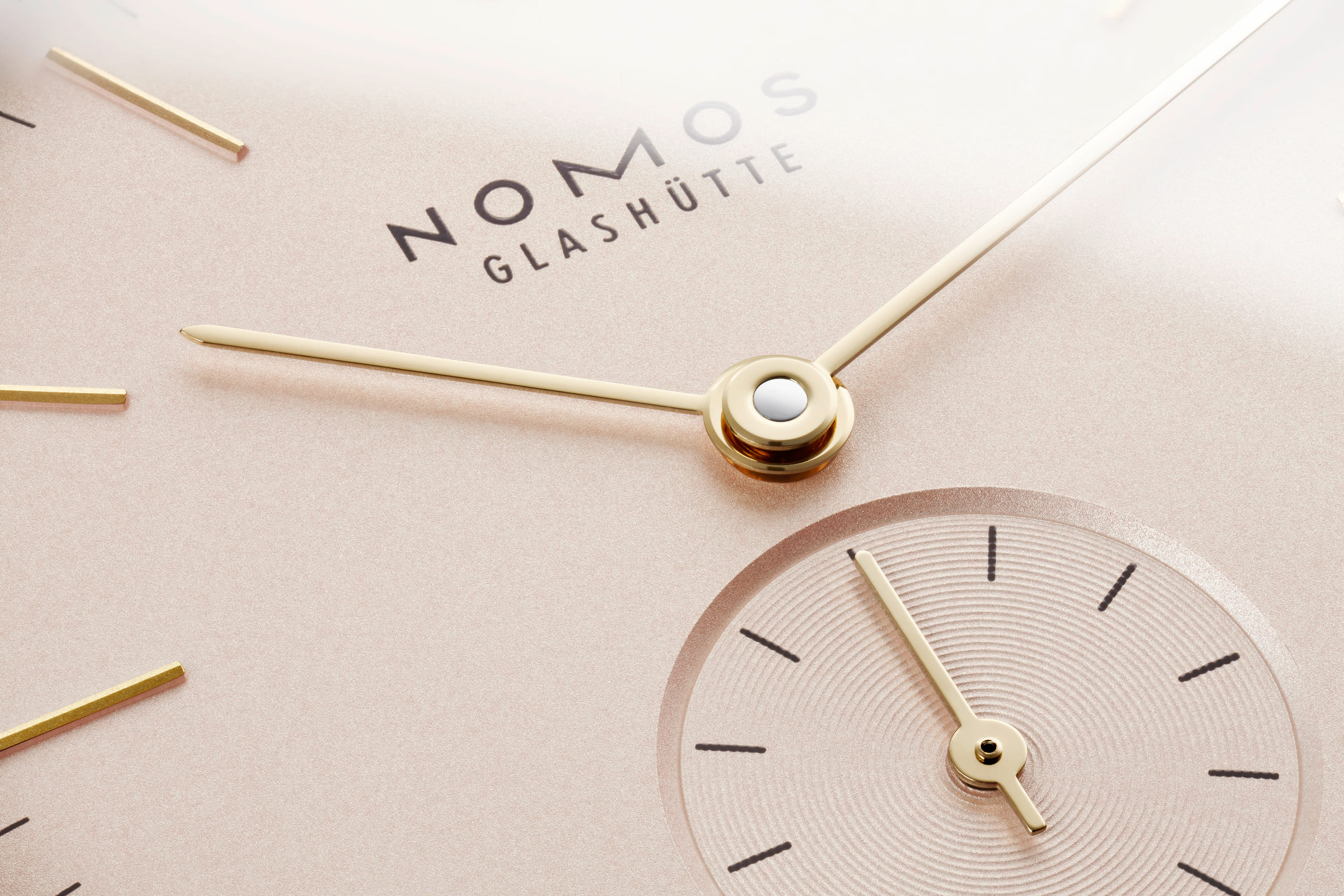 NOMOS Glashütte / Orion 33 rose / OR1A3GR233　325 小さいながら誘惑的。 ローズ・カラーでケース径33ミリのオリオン。  やや小ぶりなので、より繊細な腕元を完璧にします。  ほのかに赤らんだ明るいローズカラーダイヤル、ローズゴールドのインデックスと針、明るい色合いのベロアレザーのストラップの組み合わせは、ジュエリーとも完璧に調和し、目も腕元も楽しませてくれます。  手作業で作られる手巻きのアルファ キャリバーは高い精度で評価されています。時計は2日に一度巻き上げれば大丈夫です。