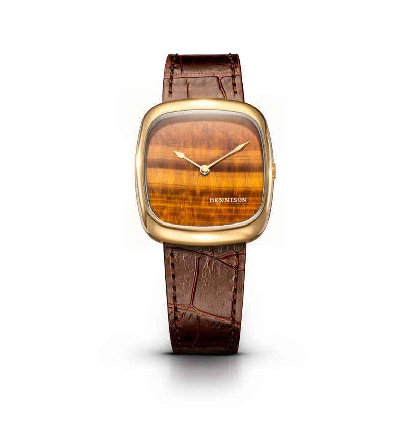 ALD Collection　Natural Stone Tiger Eye In Gold　ALD-G-ST03-BRN-R-GBKL　ダイヤルには天然タイガーズアイ（虎目石）を採用。温かみのあるブラウンゴールドの色調と、奥行きのある独特な模様が特徴で、一本ごとに異なる表情を楽しめます。丁寧にカット・ポリッシュされた天然石が、控えめながらも確かな存在感を放ちます。 ケースはゴールドPVD仕上げのステンレススチール製。37mm × 33.5mm、厚さ約6.05mmのスリムなプロポーションが、ドレスウォッチとしての品格と日常使いの快適さを両立。型押しのブラウンレザーストラップと、ケースの曲線美に呼応する特別仕様のピンバックルが、全体の統一感を高めています。