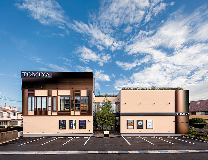 「TOMIYA 倉敷店」は外壁の一部にブラウンのパネルを配置。エントランスの正面と屋上には緑が植えられており、心地よい外観になっている。