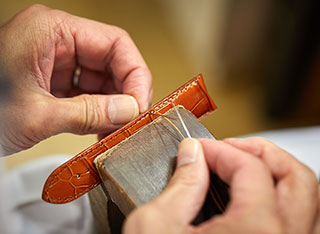 カットされた革に芯材などを接着し、コバを手縫いで仕上げる