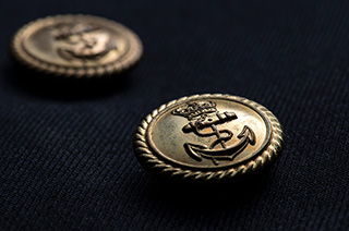 ダブルの前身頃には8個の金ボタンが縫い付けられ、そこには海軍を象徴する錨（いかり）と王冠がレリーフされている